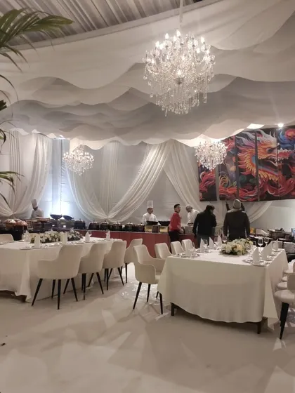 Another angle of the all-white dinner setup, showing the live food stations integrated into the decor. A pop of color from the wall art adds a point of interest while maintaining the overall sophisticated white theme.