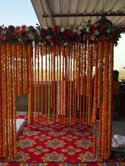 The marigold string mandap viewed from the side, showing the structure and the seating arrangement inside.