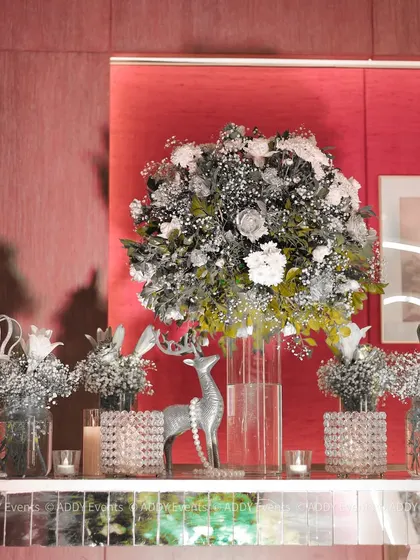 A closer look at the decor elements on the welcome console, featuring a silver deer figurine, crystal-studded candle holders, and arrangements of white and silver-dusted flowers. Every detail is curated to fit the royal theme.
