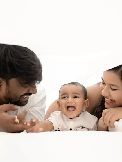 A family playing peek-a-boo under a white sheet. The baby's delighted laugh is the heart of this incredibly fun and creative family portrait.