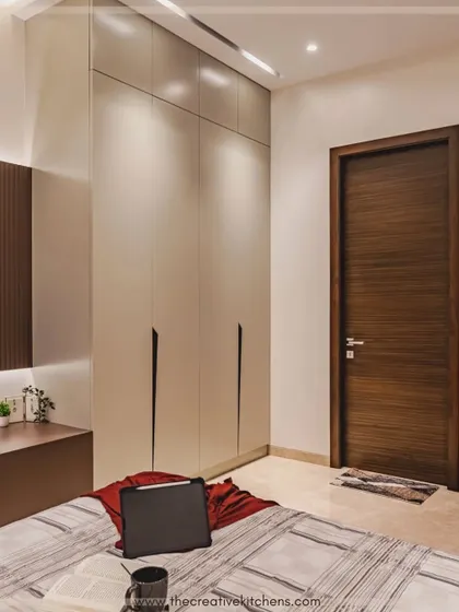 Another view of the matte lacquer wardrobe, showing how it integrates with the bedroom's overall aesthetic. Its clean, unobtrusive design complements the modern TV unit and warm tones of the room.