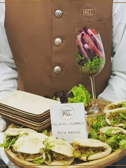 A creative presentation of Falafel Hummus Pita Bread. The mini pita pockets are filled with freshly made falafel and hummus, accompanied by a glass of crisp vegetable sticks for a healthy and interactive appetizer.