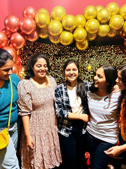 Candid moments are the best. A group of friends sharing a laugh in front of the decorated photo wall.