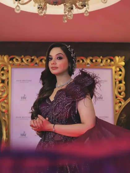 A full-length portrait of the bride in her stunning purple gown, framed by a golden archway. This shot captures the grandeur and elegance of her complete bridal look.