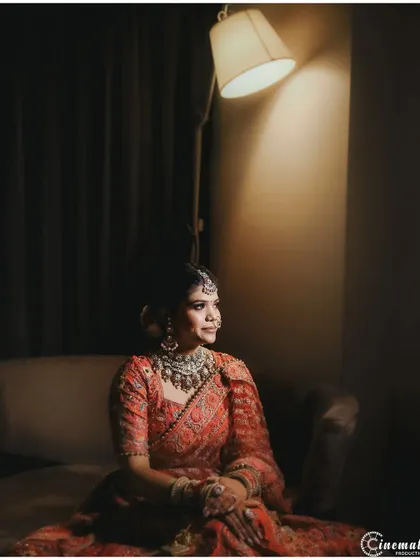 A moody and artistic bridal portrait. The single lamp creates dramatic lighting, highlighting the bride's thoughtful expression.