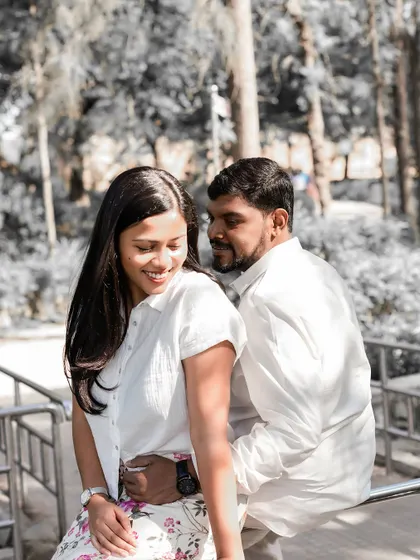 A candid shot of the couple sharing a lighthearted moment in a park, with selective color highlighting their joy.