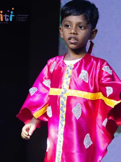 A boy in a flowing pink and yellow costume performs as part of the Vayu (Air) segment.
