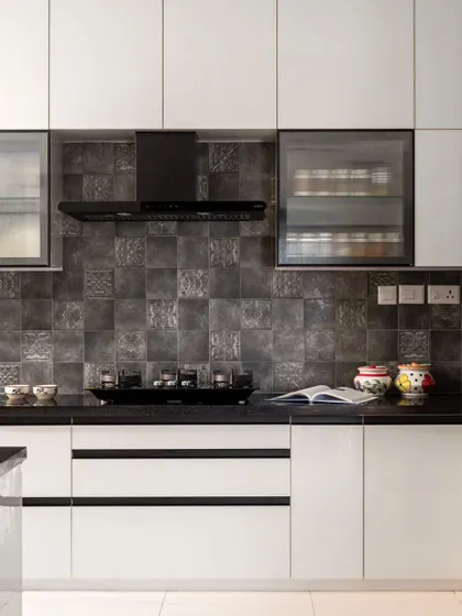 A closer look at the 'Muditā' kitchen, highlighting the sleek black hardware and integrated chimney. The design is minimalist, clean, and highly functional.