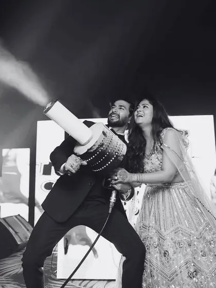 Let's make some noise! The couple takes control of the CO2 cannon, adding a blast of energy and fun to their sangeet after-party.