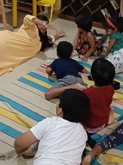 A storyteller uses playful movements and expressions to act out a scene, much to the delight of the children.