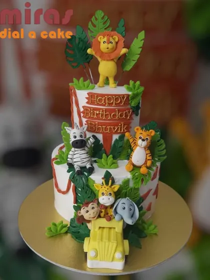 This two-tier jungle safari cake is packed with adventure, featuring a lion, tiger, zebra, and more. The details, from the jeep at the base to the lush fondant leaves, create a fun and wild scene for a birthday boy.