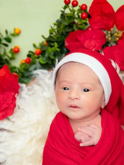 This little one is ready for the holidays. The bright red Santa hat and poinsettia wreath create a wonderfully festive and colorful portrait.