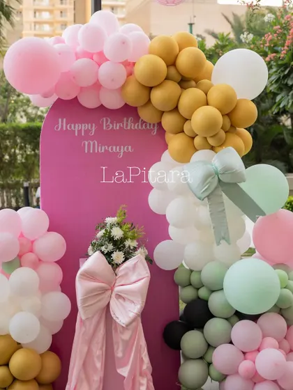A modern and colorful balloon arrangement with a large pink bow, serving as a vibrant photo backdrop.