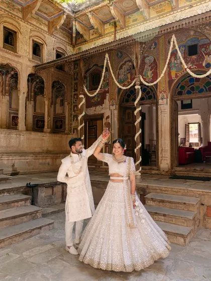 A playful dance in the courtyard of a Rajasthani haveli, where the couple's white outfits stand out against the intricate architecture and traditional art.