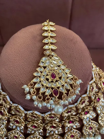 A close-up of the maang tikka from the modern ruby choker set. The design is delicate yet makes a statement.