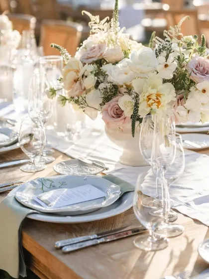 A detailed place setting with a custom menu card and delicately patterned plates. The soft sage green napkin adds a subtle touch of color to the neutral palette.