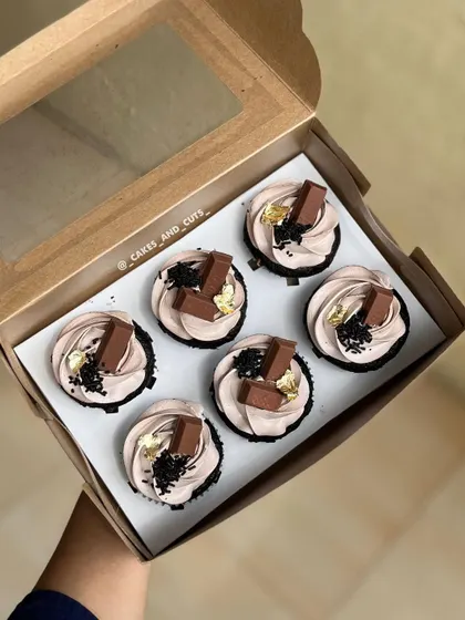 A box of delicious KitKat-topped cupcakes with a touch of edible gold leaf for elegance.