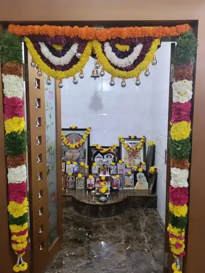 A decorated pooja room with idols and pictures adorned with garlands. I ensure the decor enhances the spiritual ambiance of the space.