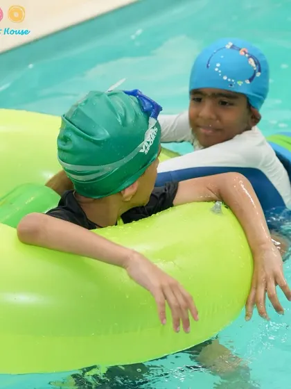 Friends helping each other out with a floatie. Our classes encourage teamwork and support among students, creating a positive learning environment.