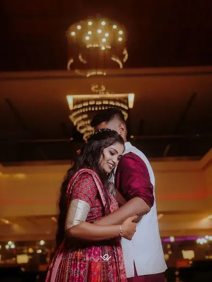 A romantic low-angle shot of a couple embracing in a beautifully lit hall, perfect for an engagement or reception.