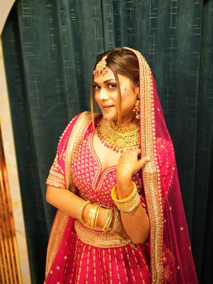 A smiling bride in her rani pink lehenga. This candid shot captures the joy and confidence that comes from wearing an outfit you truly love.