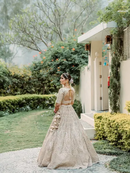 A beautiful back-shot of the bride in her elegant pastel lehenga, showing off the intricate details of her outfit and hairstyle.