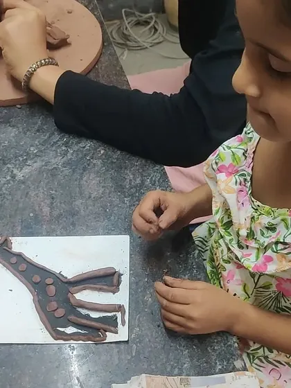 A young artist works on her clay enhanced silhouette. This activity encourages children to think about what makes them unique while exploring different textures and shapes with hand building techniques.