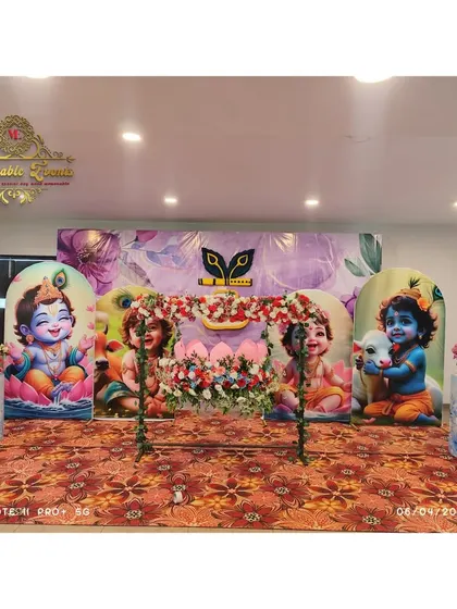 A full view of the Krishna-themed naming ceremony, showing the custom backdrops and the floral-decorated cradle in the center.