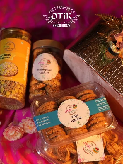 A festive hamper for Diwali, showcasing jars of multigrain cookies and ragi mixture alongside a box of kaju biscuits, all packed in a decorative box.