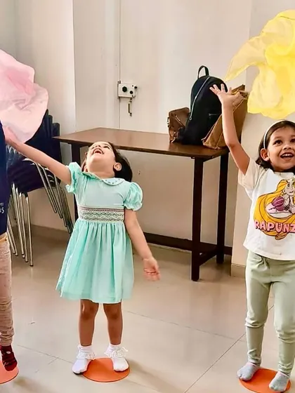 Three girls express their joy with colorful scarves during a movement exercise. Music education is about fostering creativity and emotional expression.