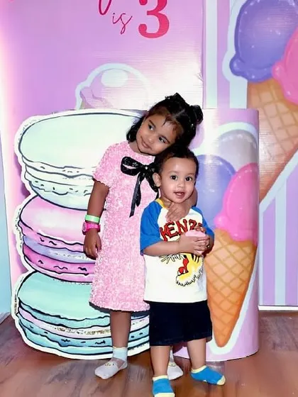 Siblings pose in front of a sweet-themed backdrop.