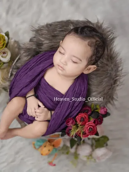 The innocent peace of a sleeping newborn is a sight to behold. This overhead shot in a cozy, fur-lined basket creates a beautiful and artistic portrait.