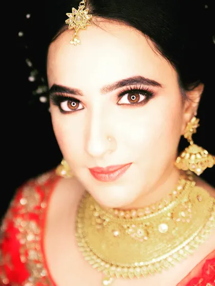 A stunning close-up bridal portrait. The focus is on her expressive eyes and the magnificent gold jewelry that completes her wedding day look.