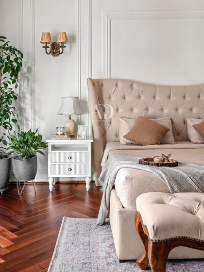 A close-up detail of the bedside, showing the classic white nightstand and elegant wall sconce. I believe in incorporating every little detail to match the client's taste and transform a house into a home.