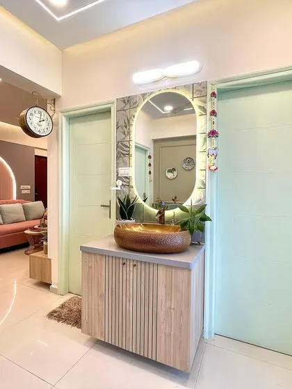 The common wash basin area is designed with a wooden vanity, a beautiful stone-finish sink, and a backlit mirror, creating a stylish and functional space for guests.