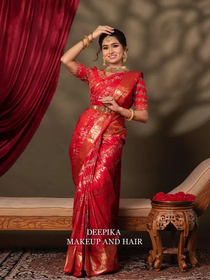 A full-length shot of the bride standing, showing the beautiful fall of the red silk saree. She looks like a picture of grace and tradition.