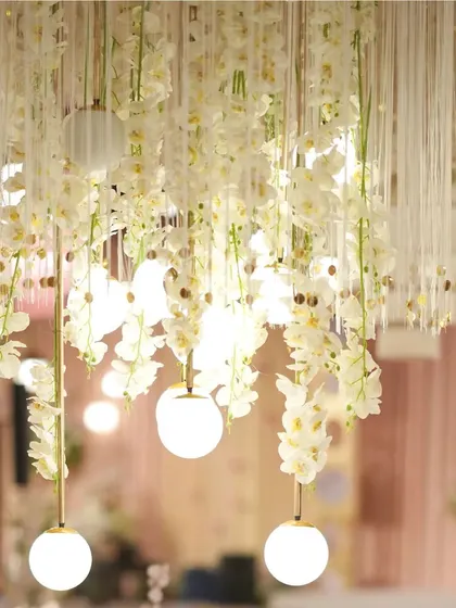 A close-up of the delicate lighting from our 'Midsummer Dream' theme. Cascading white orchids are intertwined with glowing globe lights, creating an ethereal and romantic effect that transforms the entire space.