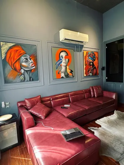 The combination of the red leather sofa, animal hide rug, and bold artwork creates an eclectic and personality-filled living space.
