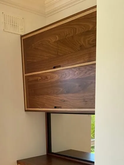 The upper cabinet doors closed, showing the beautiful, continuous grain of the solid walnut. The thin oak inlay provides a subtle border that frames the piece.