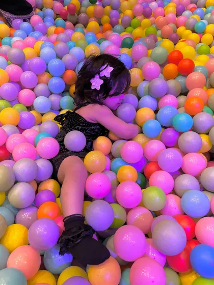 A stylish moment of fun in the ball pit. Even in a party dress, the fun doesn't stop!