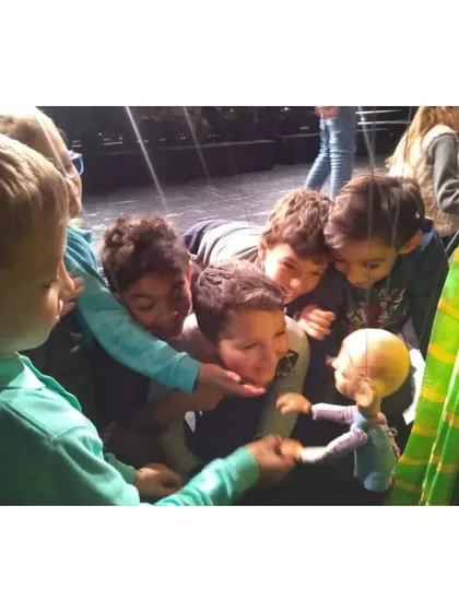 A group of curious children gather around to get a closer look at one of our handmade puppets after an international performance.