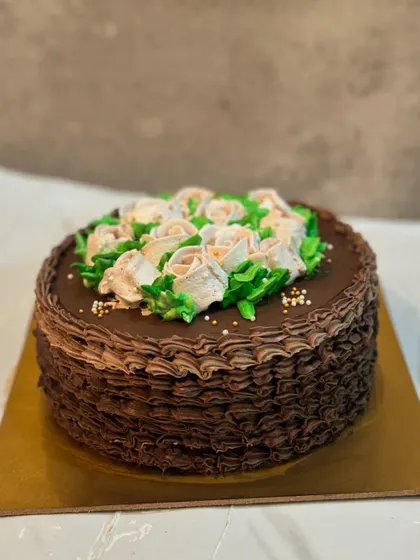 A beautiful chocolate cake with a basket weave piping technique around the sides, topped with delicate buttercream roses.