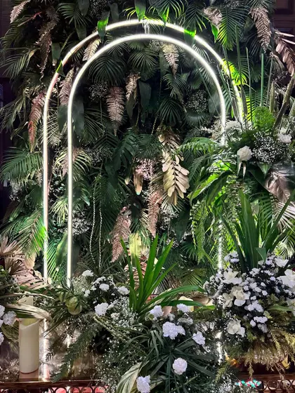 A beautiful composition of white flowers and lush greenery, with a neon arch adding a modern, glowing touch to the botanical arrangement.