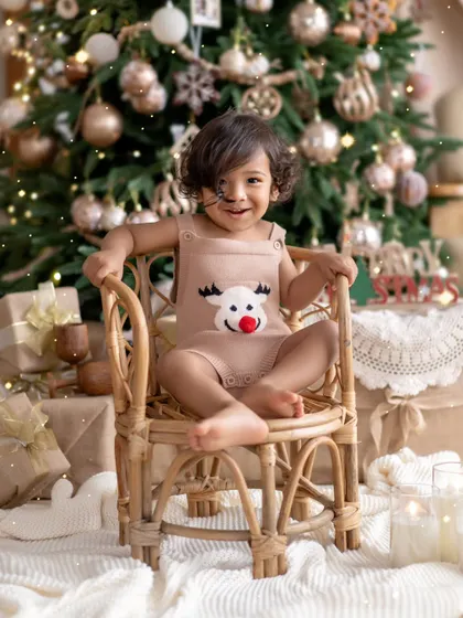 The cutest little reindeer you've ever seen. This toddler's happy smile in front of the Christmas tree is the perfect way to capture the joy and wonder of the holidays.