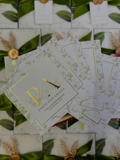 A fan of the invitation cards for Parth and Amisha, showcasing the consistent and elegant design across all inserts for their wedding functions.