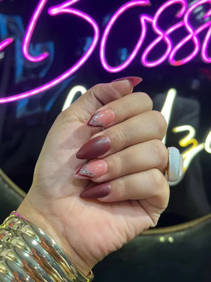 A closer look at this custom stiletto nail art, showcasing the clean lines and the contrast between the matte red-brown polish and the sparkling silver glitter accent.
