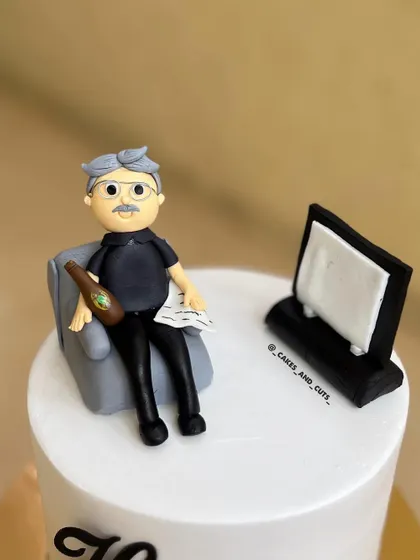 A custom fondant topper we made for a 76th birthday cake, showing the birthday person relaxing in their favorite chair. We teach figure modeling in our fondant classes.
