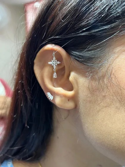 A cross-shaped hanging adds a touch of faith and fashion to this ear, balanced by a simple, sparkling wing stud on the tragus.