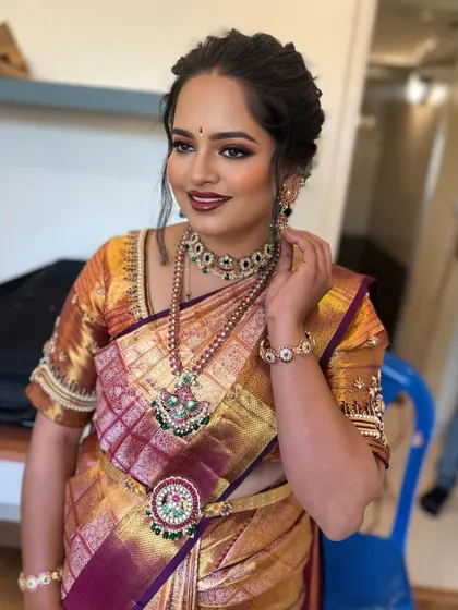 A classic South Indian bridal look with a beautiful gold and maroon saree. The eye makeup is a soft smokey brown with a touch of shimmer, paired with a bold lip for a timeless feel.
