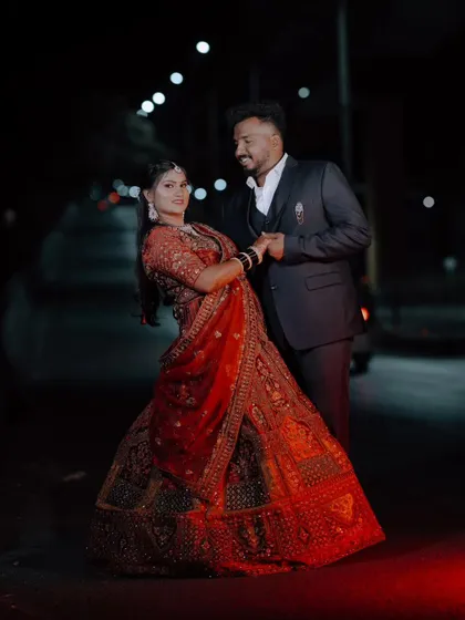 A romantic outdoor shot of the couple at night, with the bride's red lehenga beautifully lit.